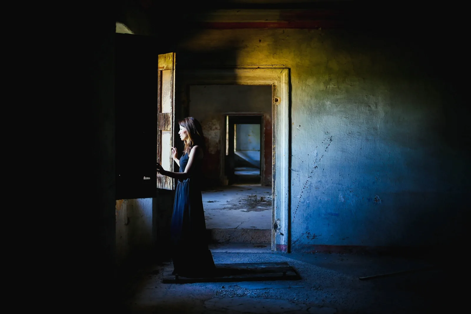 A figure at a window in an old house, rooms opening into rooms