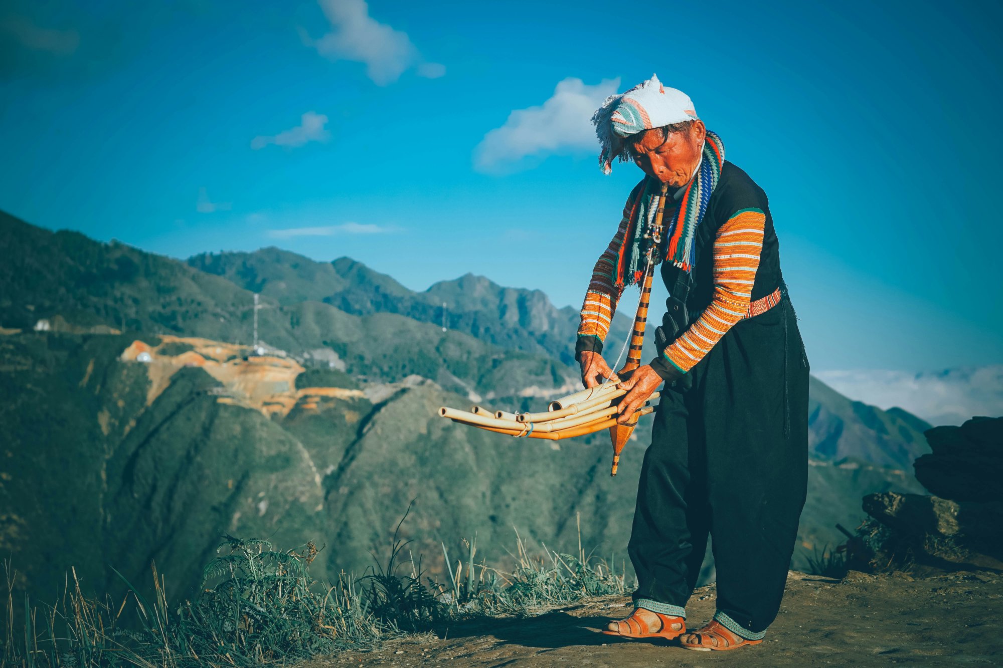 Hmong elder playing traditional instrument in mountain landscape – keeper of soul-calling traditions