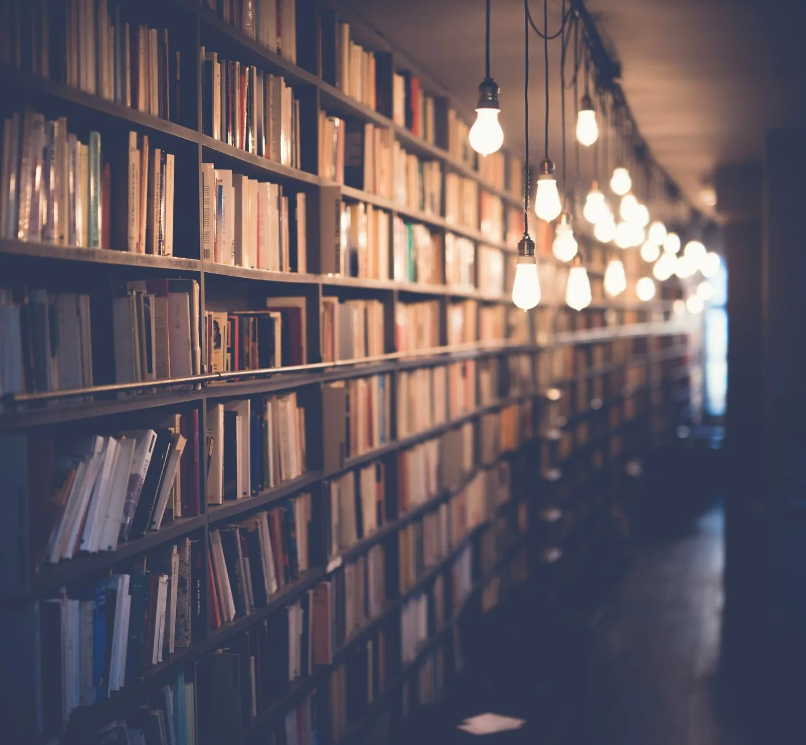 Ancient library with warm Edison bulbs illuminating endless bookshelves, a gateway to dream wisdom